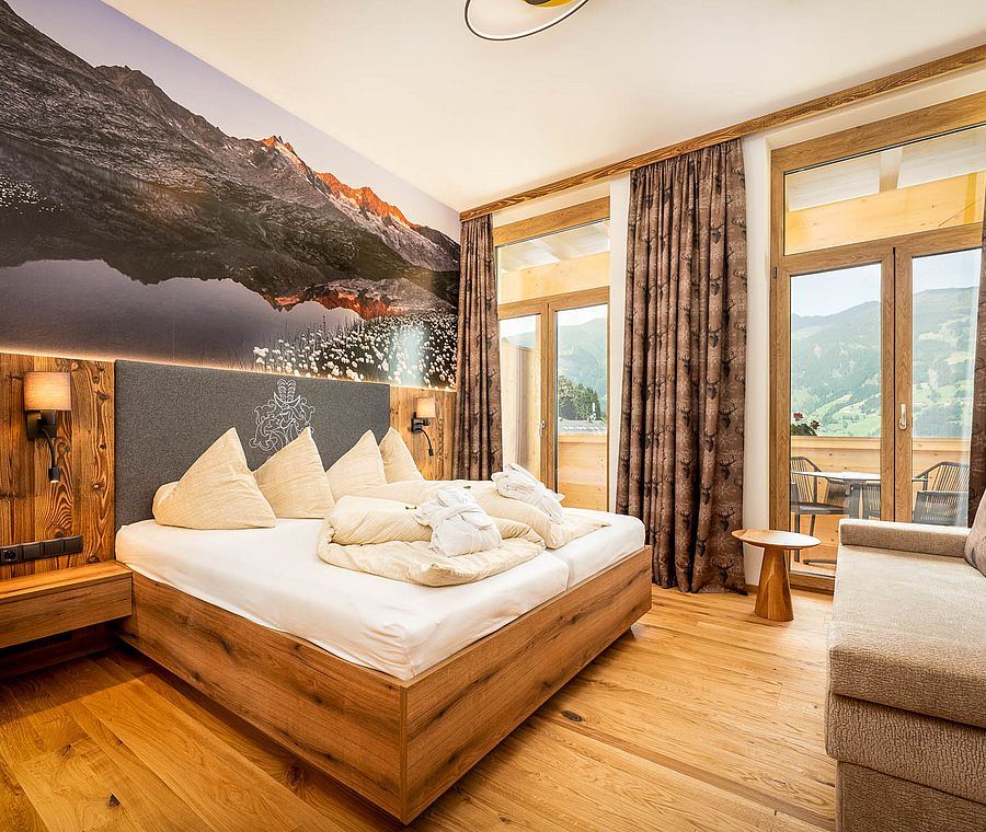 Hotel room with large wall mural, double bed, sofa and balcony view