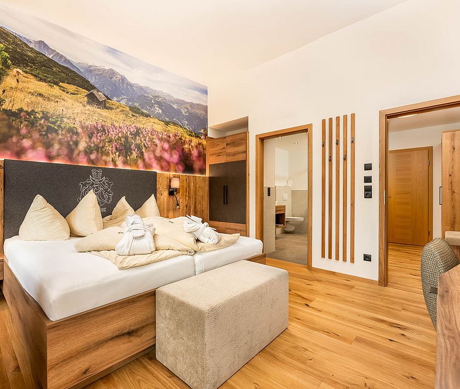 Room with mountain picture on the wall, wooden floor, view to bathroom, modern furnishings