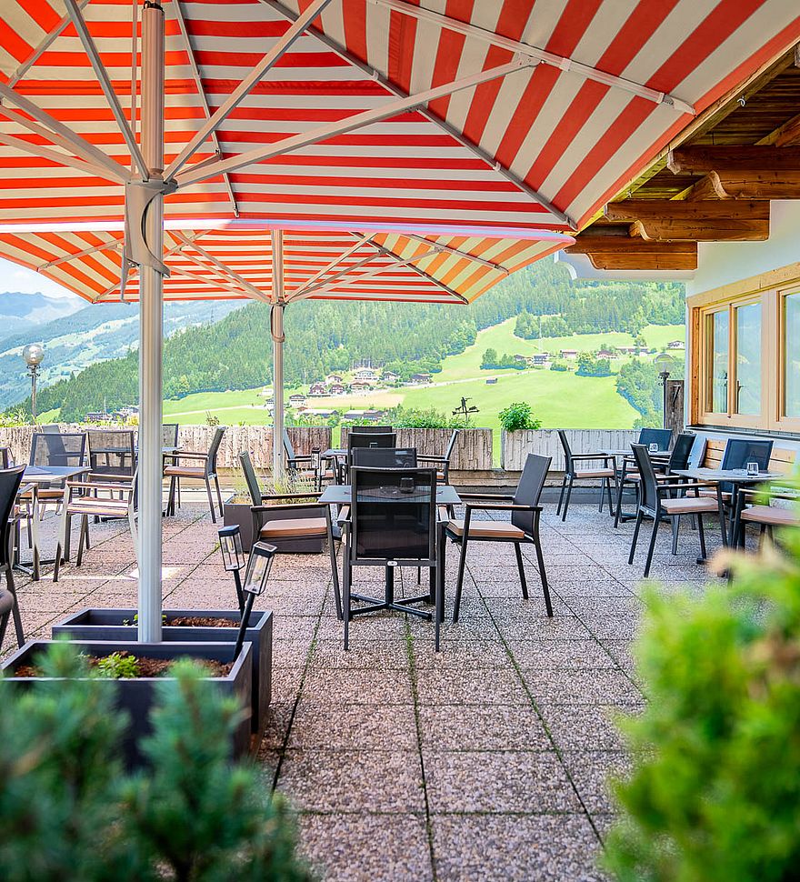 Zonnig terras bij gasthof met gedekte tafels en uitzicht op het Tiroolse berglandschap