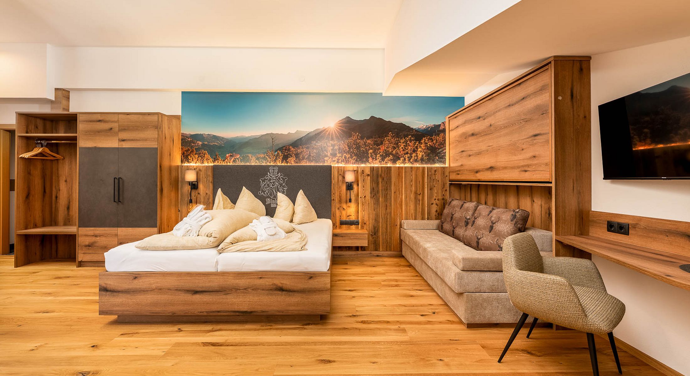 Gemütliches Zimmer mit Doppelbett, Sofa, Kleiderschrank und Berglandschaft an der Wand