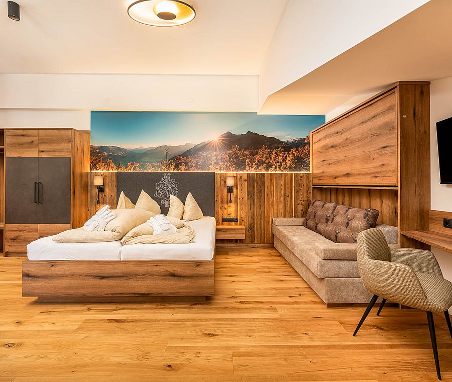 Cozy room with double bed, sofa, wardrobe and mountain landscape on the wall