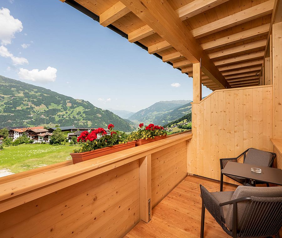 Wooden balcony with table, chairs, flowers and view of the valley and mountains