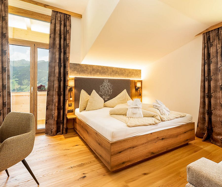Hotel room with double bed, wooden floor, balcony view and brown curtains